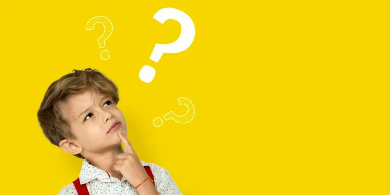 Un enfant songeur entouré de points d’interrogation