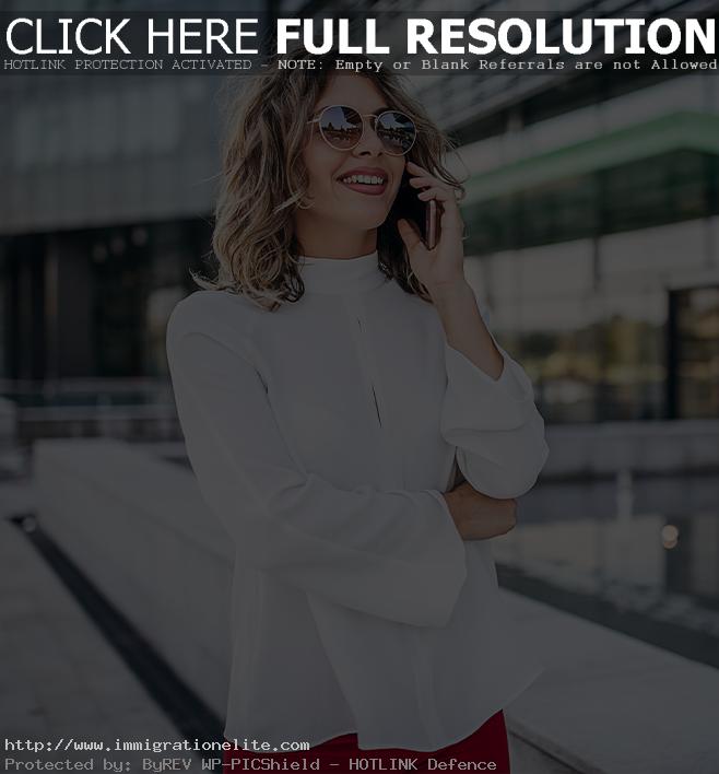 A business woman wearing sunglasses talking on a phone.